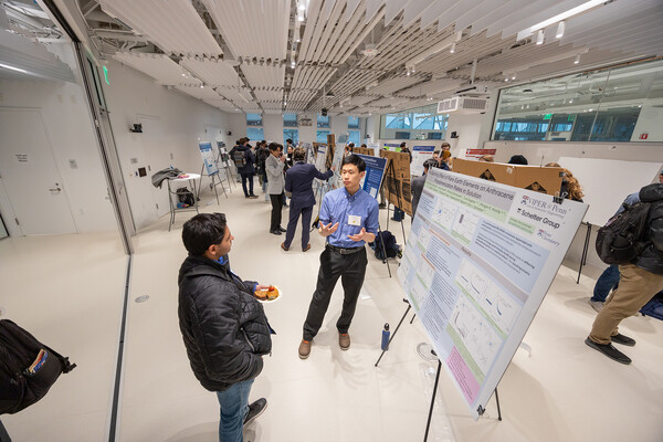 Two people have conversation in front of research poster.