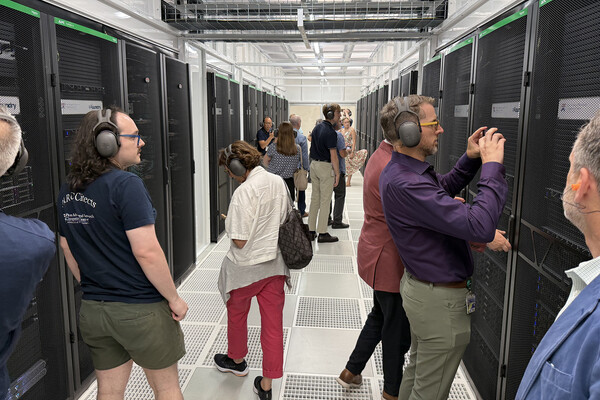 People in hallway surrounded by computing equipment.