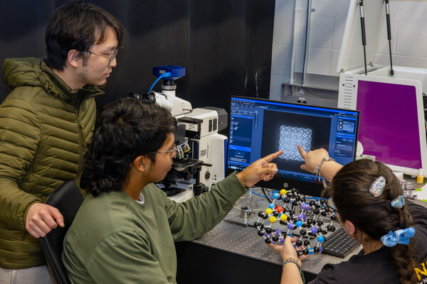 Three members of the Tertuliano lab looking at a computer in the lab.