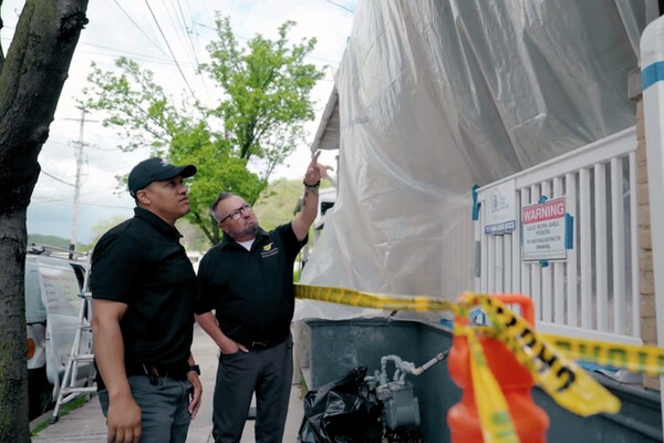 Two members of a lead abatement team surveying a house under lead abatement treatment.