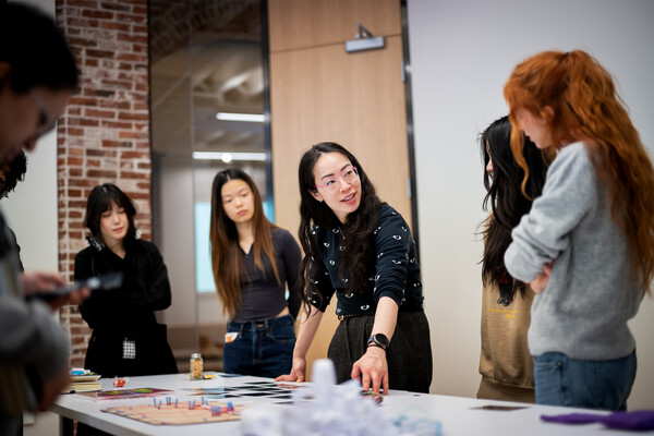 Ani Liu standing at a table speaking to students.