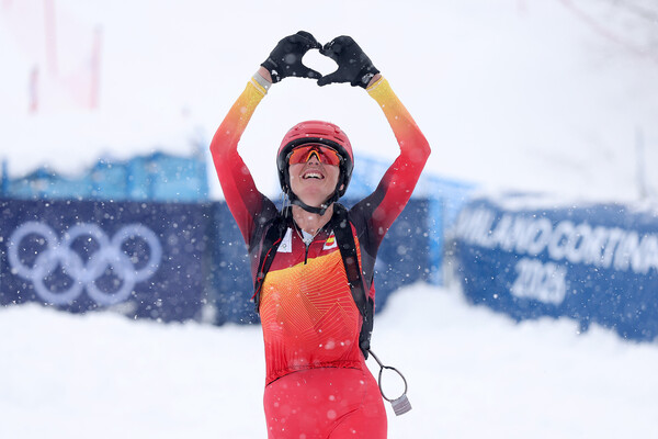 An Olympic skiier making a heart sign with their hands post ski run at the Winter Olympics.