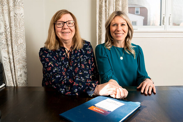 Jen Brady (right) and her mom seated at a kitchen table.