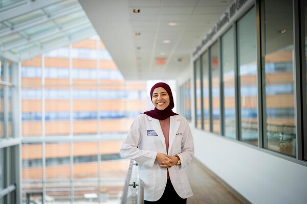 medical student Bayan Galal standing in an atrium wearing a white coat 