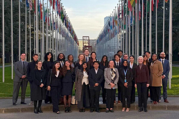 Members of the Perry World House Geneva cohort standing in front of UN flags.