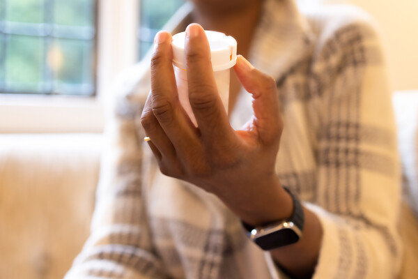 A person holding a prescription pill bottle in their hand.