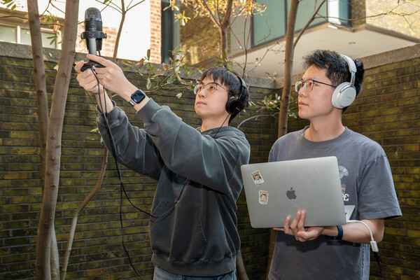 Yiduo Hao and a researcher using a microphone and a laptop outdoors.