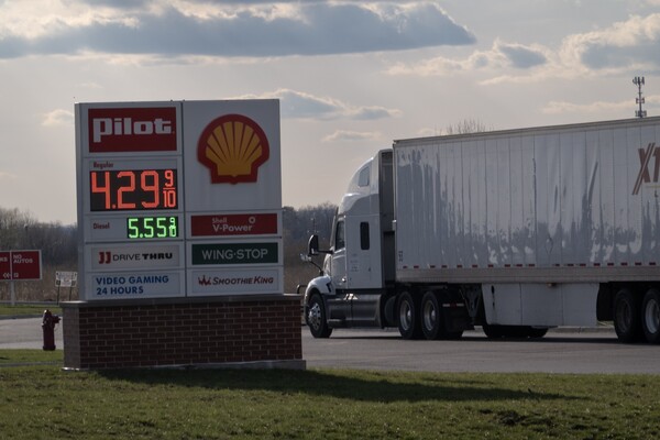 Fuel prices are displayed at a truck stop next to a parked truck.
