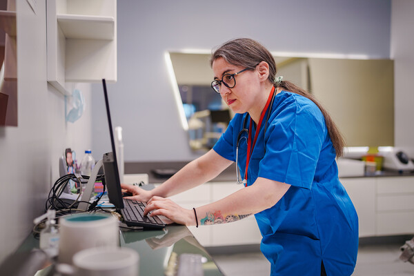 A nurse typing on a desktop computer.