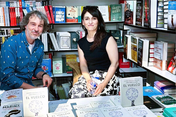 Jordi Pérez Colomé and Sandra González-Bailón seated at a bookstore with copies of their book.