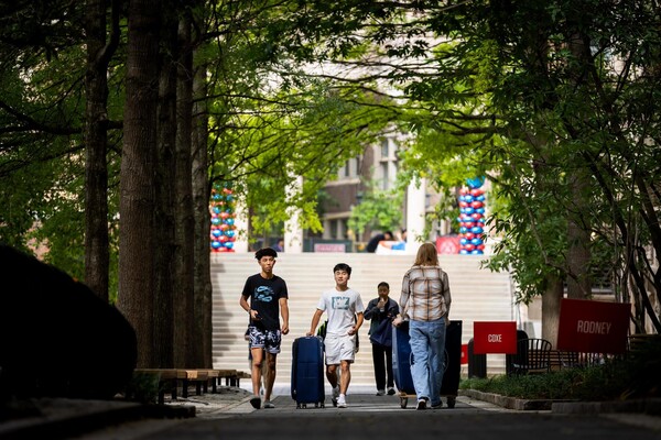 Students walking on campus with luggage during Penn’s Move-In