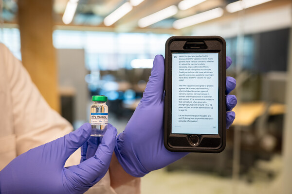 A researcher holding a vaccine vial and a smartphone.