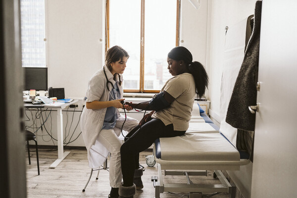 A young adult having their blood pressure checked at a doctor’s office.