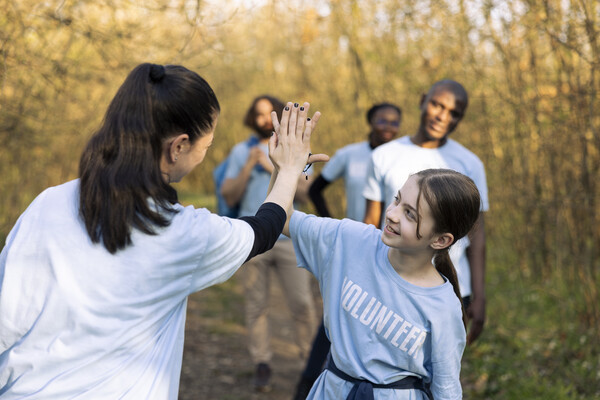 An adult giving a child a high five in nature.