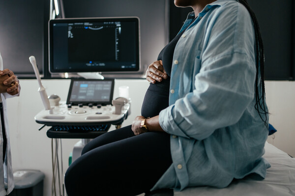 A pregnant person holding their belly at a prenatal checkup.