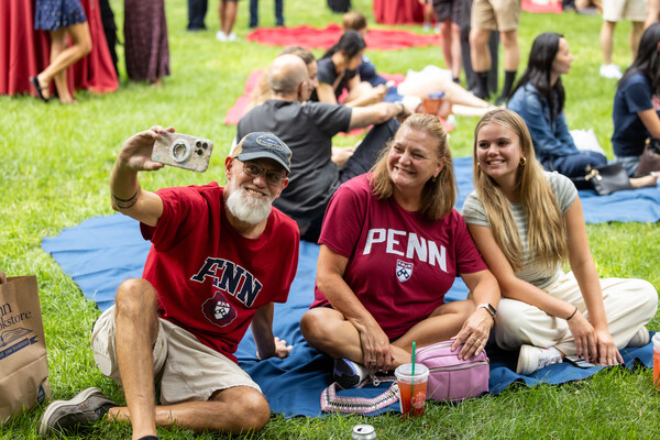 A penn student and their parents taking a selfie at the welcome picnic.