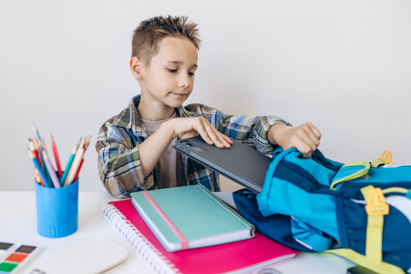 A student packs his bookbag and gets ready for class.