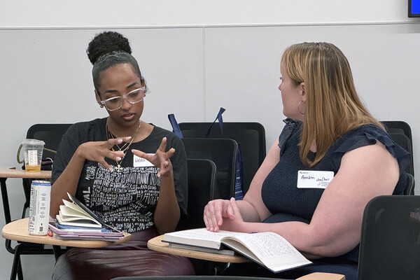 Two members of the Philadelphia Writing project seated in a classroom in a discussion.
