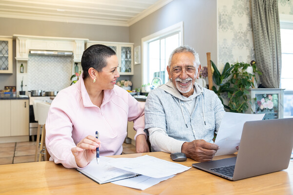 Two senior citizens doing retirement planning paperwork at the dining table.