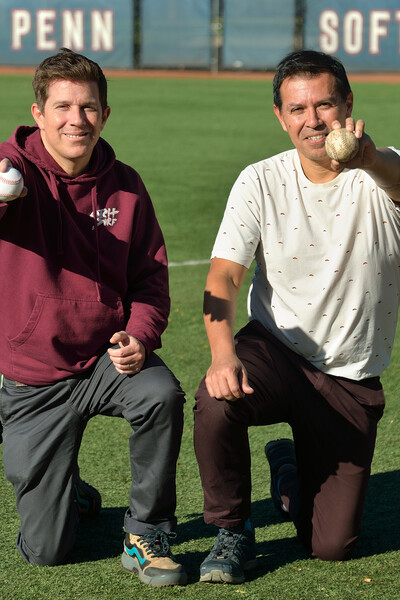 Researchers Douglas Jerolmack and Paulo Arratia kneel on a field at Penn, each holding a baseball