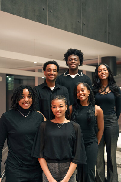 A group of six students wearing black, standing on the stairs so all our visible 